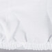 A white L.A. Baby crib pad cover with ruffles and a seam.