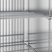 A metal shelf in a True reach-in freezer with wire racks.