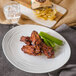 A plate of chicken wings, celery, and fries on a ivory oval melamine platter with a textured rim.