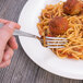 A Oneida Scroll stainless steel dinner fork on a plate of spaghetti.