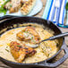 A Lodge cast iron skillet with chicken and vegetables in it.