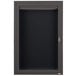 A black metal cabinet with a key and a glass door with a black letter board inside.