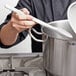 a person holding a spoon in a pot