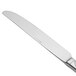 A close-up of a Oneida Scroll stainless steel dinner knife with a silver handle.