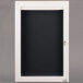 A white frame with a black board behind a window in a white door.