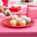 A person holding a cupcake on a GET Cranberry Diamond Harvest oval platter.