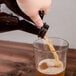 A hand pouring beer from a Libbey Amber Growler into a glass.