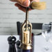 A hand using the brush on a Franmara open-frame corkscrew with a cork.
