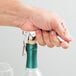 A hand uses a Franmara Duo-Lever corkscrew with a white enamel handle to open a bottle of wine.