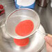 A Tablecraft fine tin single mesh strainer holding a red substance over a bowl.