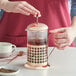 A woman using an Acopa copper French coffee press to pour coffee.