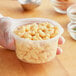 A hand holding a ChoiceHD translucent plastic deli container of macaroni and cheese.