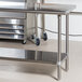 A stainless steel Advance Tabco work table with undershelf and wheels.