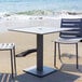 A BFM Seating titanium silver square table with two chairs on the beach.