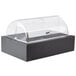 A black Vollrath food display platter with clear lid on a bakery counter.