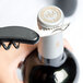 A person using a Franmara two-lever waiter's corkscrew with a black handle to open a wine bottle with a cork.