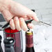 A hand holding a Pulltap's Original black and silver corkscrew over a wine bottle.