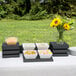 A white rectangular Vollrath Cubic bowl with brown food on a table with plates and bowls of food.