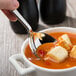 A Bon Chef stainless steel soup spoon in a bowl of soup.