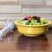 A Fiesta Sunflower china serving bowl filled with salad on a table.