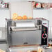 An APW Wyott vertical conveyor bun grill toaster with food inside.