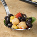 A Bon Chef stainless steel sombrero tasting spoon filled with black beans, corn, and black olives.