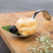 A Bon Chef Reflections bouillon tasting spoon with a pastry on it.