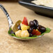 A Bon Chef Reflections bouillon tasting spoon filled with food on a table.