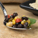 A Bon Chef Reflections silver spoon filled with food on a counter.