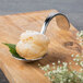 A Bon Chef curved metal bouillon tasting spoon with food on it.