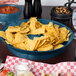 A blue bowl filled with red salsa and a bowl of chips on a table in a Mexican restaurant.