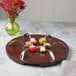A Bon Chef cherry wooden lazy susan turntable with spoons on it.