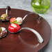 A Bon Chef cherry wooden lazy susan turntable with spoons of food on it.