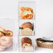 A Cal-Mil clear bread box with three sections holding loaves of bread.