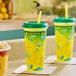 Two Clear plastic lemonade cups with lids and straws on a counter.