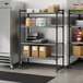 A white Cambro Camshelving unit in a kitchen with metal shelves holding boxes and containers.