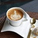 A Villeroy & Boch white porcelain cappuccino cup with a design in the foam on a plate with a pastry.