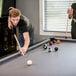 A man playing pool on a Mizerak Dakota pool table with a cue stick.