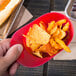 A hand holding a red mini baseball helmet ice cream/snack bowl filled with chips.