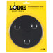 A Lodge black circular magnetic trivet in plastic packaging.