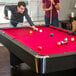 A man and woman playing pool on a Mizerak pool table.