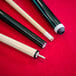 Three Mizerak pool cues on a red pool table surface.