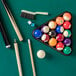 A Triumph pool table with billiard balls, cue, and a brush.