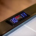 A digital clock with red numbers on an Atomic air hockey table.