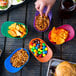 Assorted color mini baseball helmet bowls filled with snacks on a table.