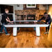 A man and woman playing air hockey on an Atomic Avenger air hockey table.