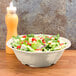 A table set with a New Yorker ivory melamine bowl filled with salad.