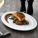 A Libbey Alpine White Porcelain platter with salmon and vegetables on a table.