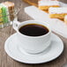 A Libbey alpine white porcelain cup of coffee on a saucer with pastries.