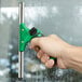 A hand holding a green Unger ErgoTec SwivelLoc squeegee on a window.